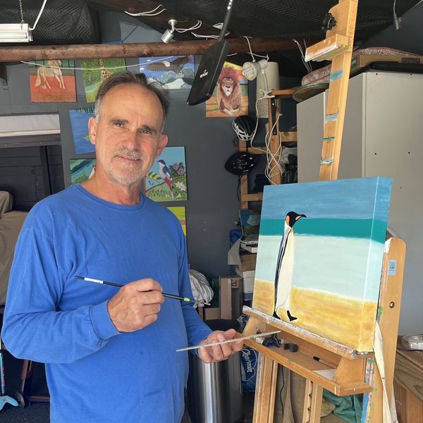 Man painting a penguin on canvas.