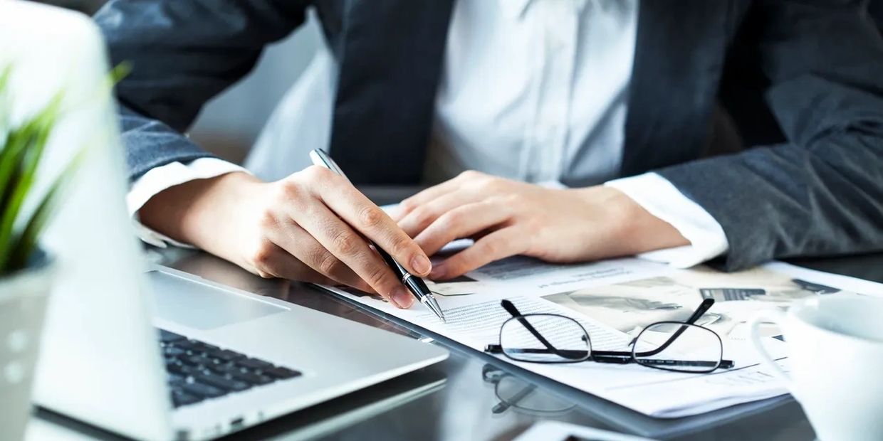 A business professional reviewing and signing documents at a desk, symbolizing strategic thinking, s