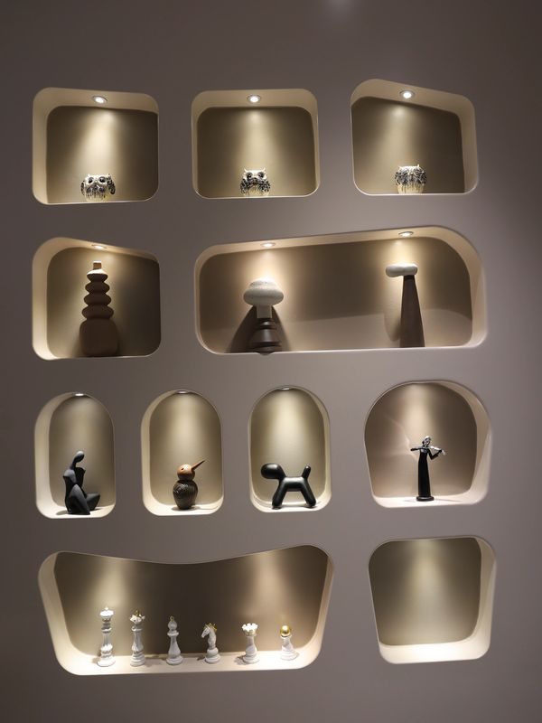Modern wall niches with artistic sculptures and chess pieces under soft lighting.