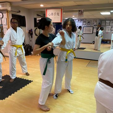 Two women karate students demonstrating defense against a grab and an arm lock. 