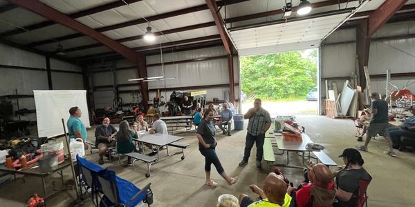 People socializing in a large indoor warehouse with open garage door.