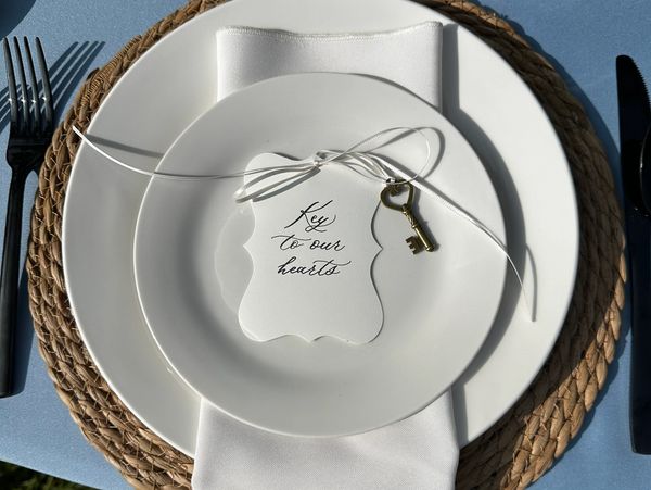 Elegant place setting with a key and note on white plates.