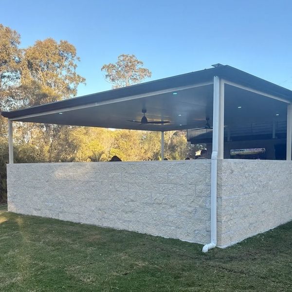 Covered outdoor patio with stone half-wall and ceiling fans.
