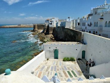 White coastal buildings with blue doors by the sea.