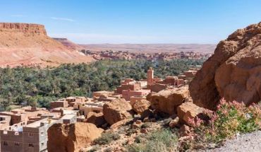 A desert village near a green valley with rocky hills.