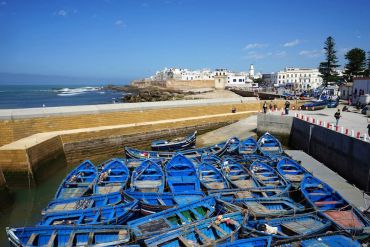 Blue boats docked in a coastal town under a clear sky.