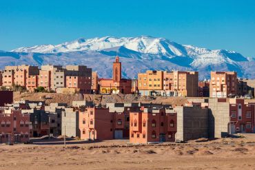 City buildings with snowy mountains in the background.