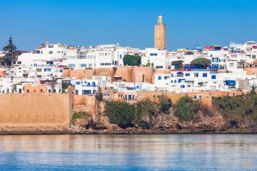 Seaside town with white buildings and a tall tower.