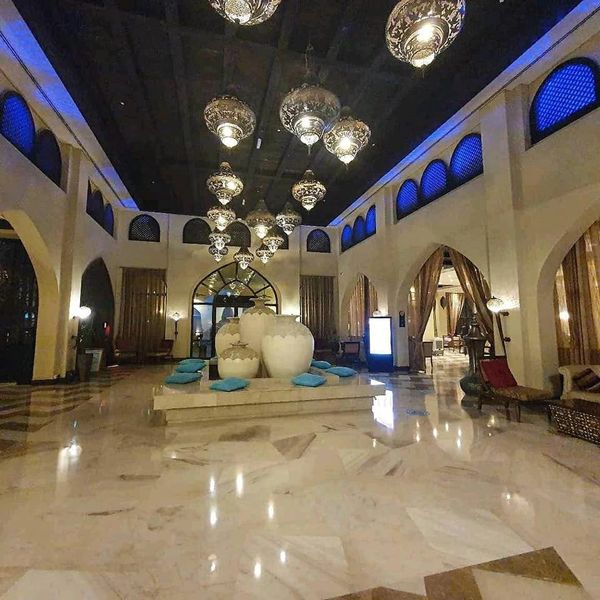 Luxurious hotel lobby with ornate lighting and large white vases.