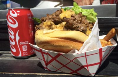 Cheeseburger with lettuce and fries served with a can of Coca-Cola.