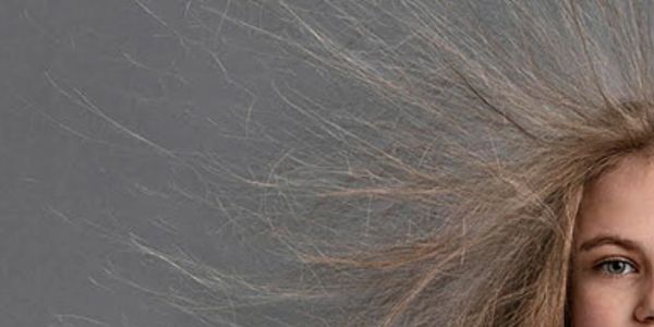 Close-up of hair strands fanning out against a gray background.