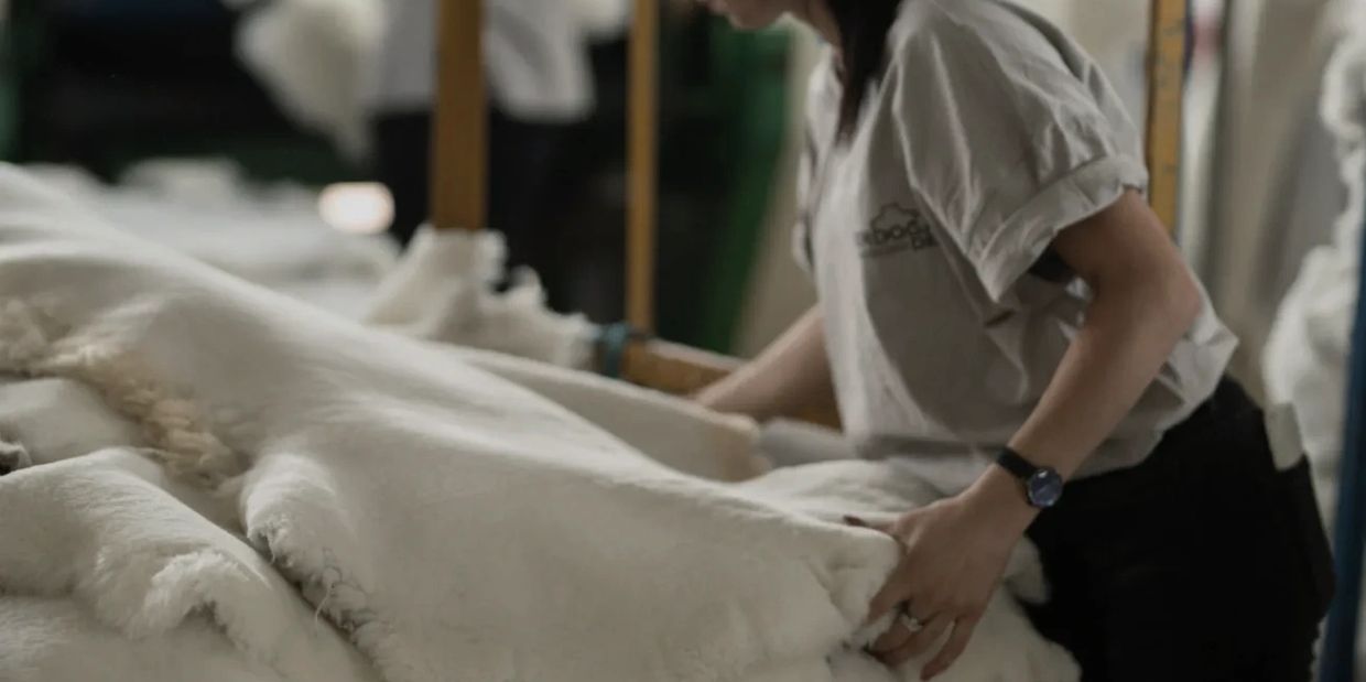 Person handling soft, white fabric or fleece indoors.