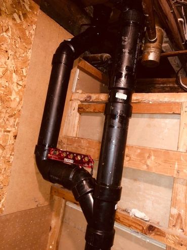 Alt Text: Black PVC drainage and vent plumbing pipe system installed within a residential wooden wal