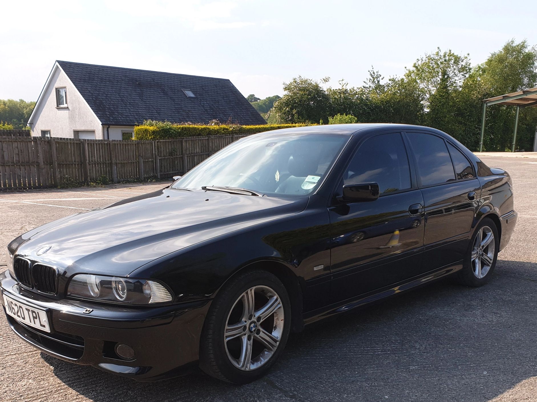 Black BMW sedan parked on a concrete surface in daylight.