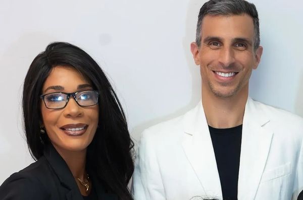 Two professionals smiling, one in black and one in white attire.