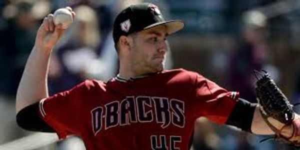 Pitcher in a Dbacks uniform winding up to throw a baseball.