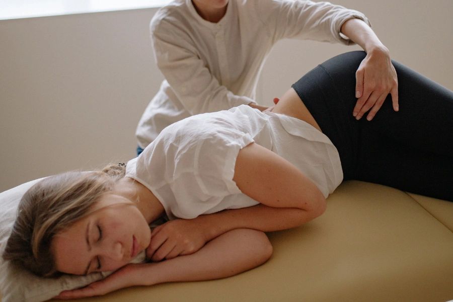 A woman receiving a gentle back massage while lying on her side.