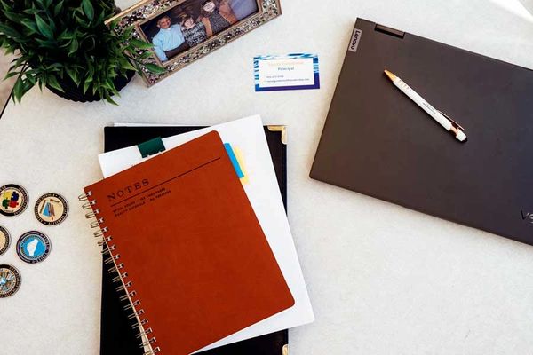 Desktop with notebooks, pens, business cards, family photo and award medals.