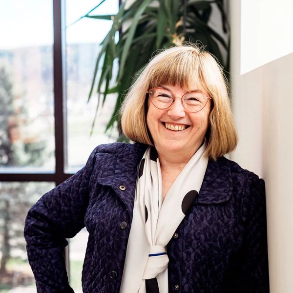 Smiling woman, financial consultant Susan Goodison, in blue jacket standing in office setting.