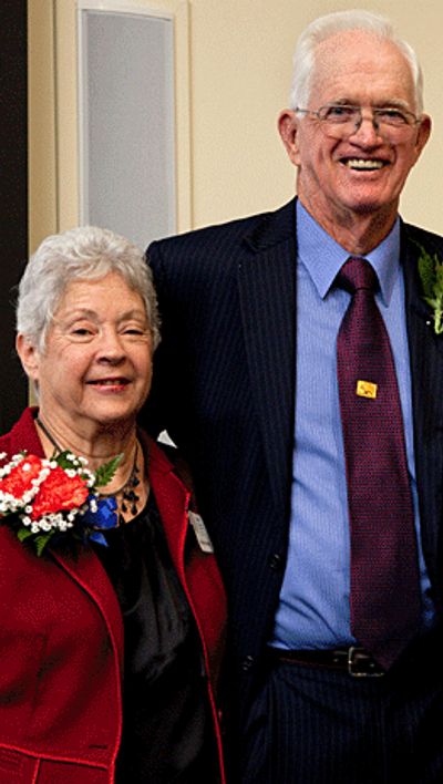 Elderly couple dressed formally, smiling with floral corsages.
