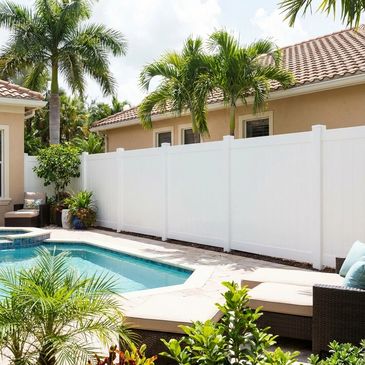 A serene backyard pool area with palm trees and white privacy fence.