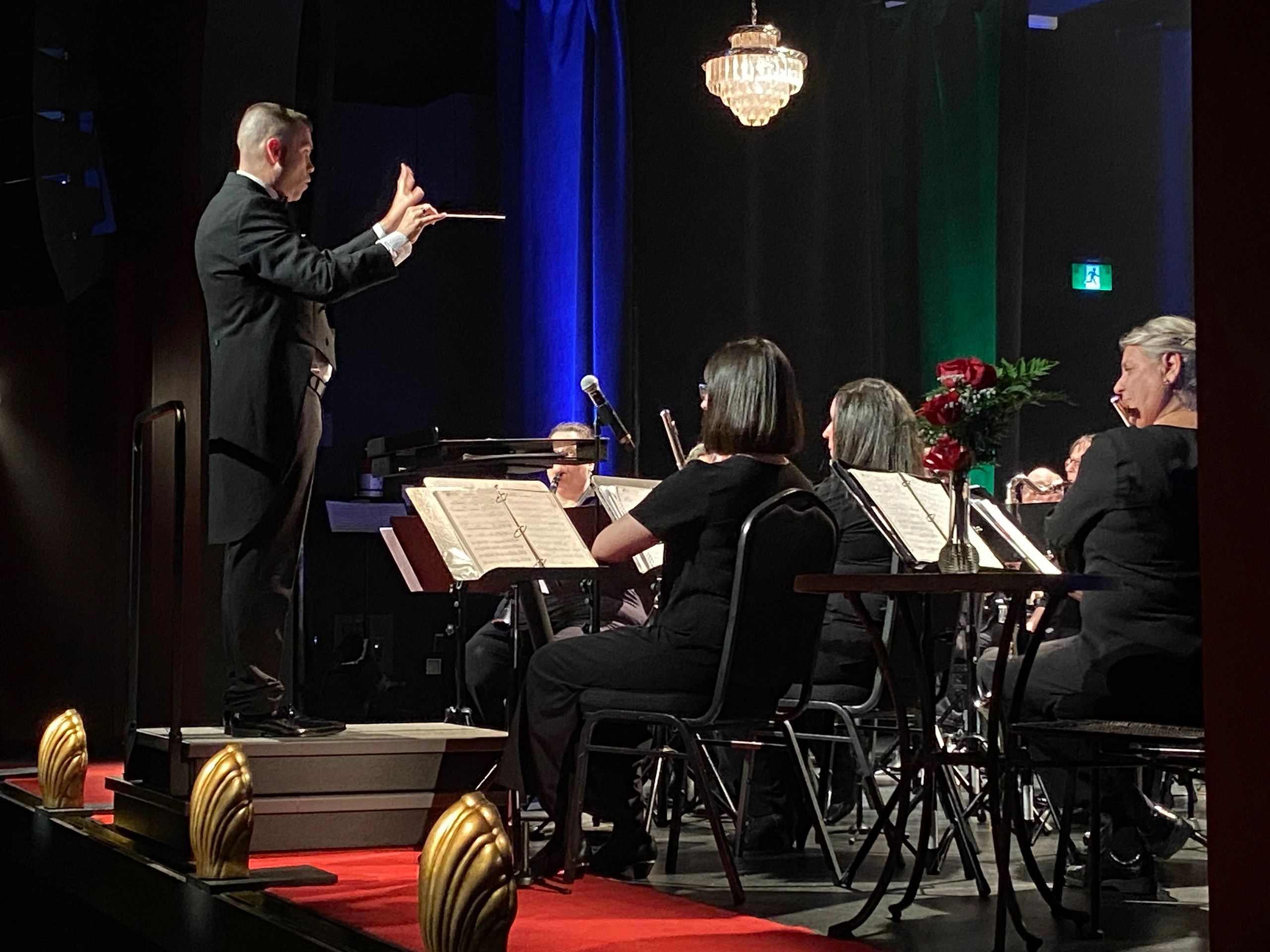 Conductor leading orchestra during a live performance on stage.