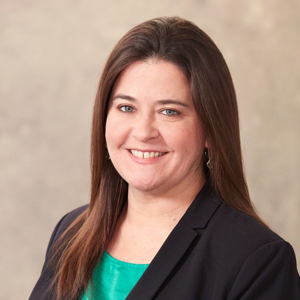 Professional woman in a blazer smiling at the camera.