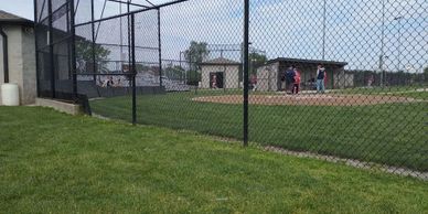 View of a baseball field behind a chain-link fence with players on the field.