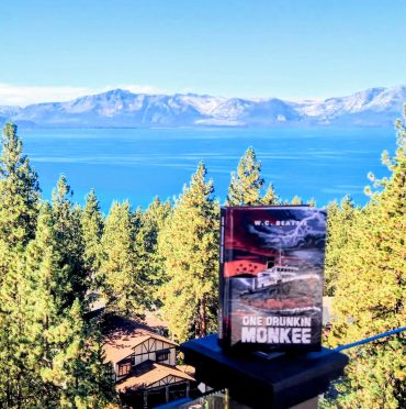 Book titled 'One Drunkin Monkee' with a scenic lake and mountain background.