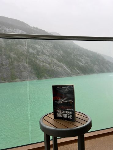 Book on a stool with scenic lake and mountain background.