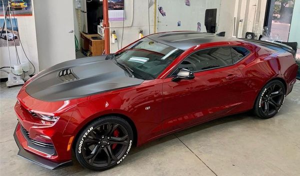 Red and black sports car parked indoors with sleek design.