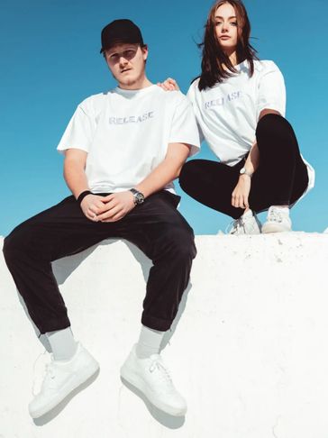couple wearing matching jeans and white off swagsync tee and giving look to camera 