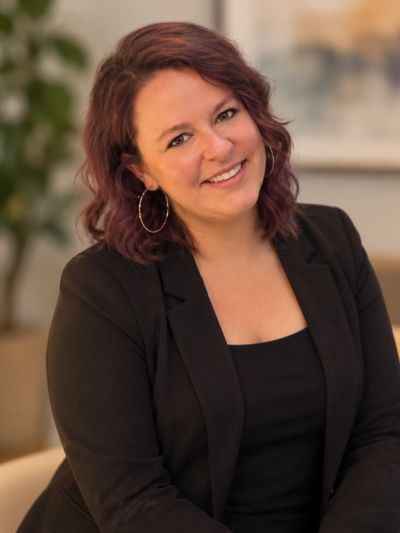 Smiling woman with curly hair in a black blazer.