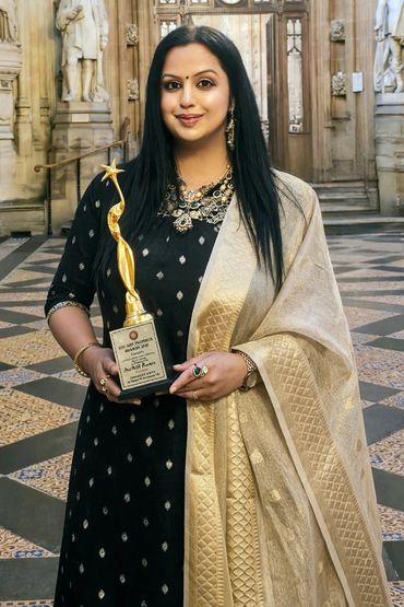 Woman in traditional attire holding a golden award trophy.