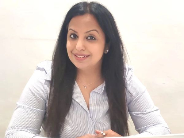 Smiling woman in a striped shirt sitting at a white desk.