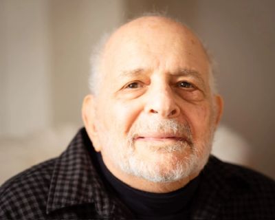 Portrait of an elderly man with a gentle smile and a white beard.