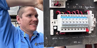 Electrician working on a circuit breaker panel outdoors.
