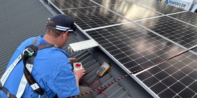 Technician installs solar panels on a roof with safety harness and tools.