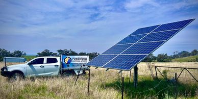 Solar panels installed in a rural field with a Powerflow service vehicle nearby.