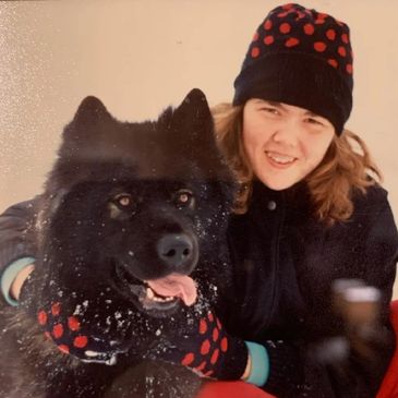 Close-up picture of teenage girl wearing matching hat and gloves with her dog. 