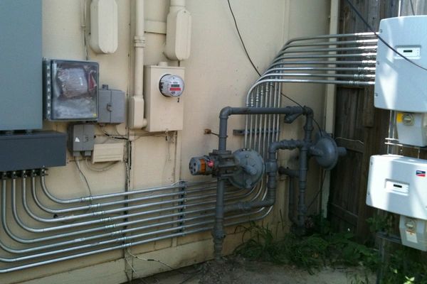 Exterior electrical meters, conduits, and piping on a building wall