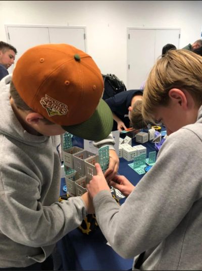 Two boys working on a project with plastic building pieces.