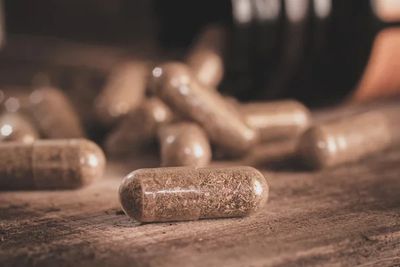 Close-up of herbal capsules on a wooden surface.