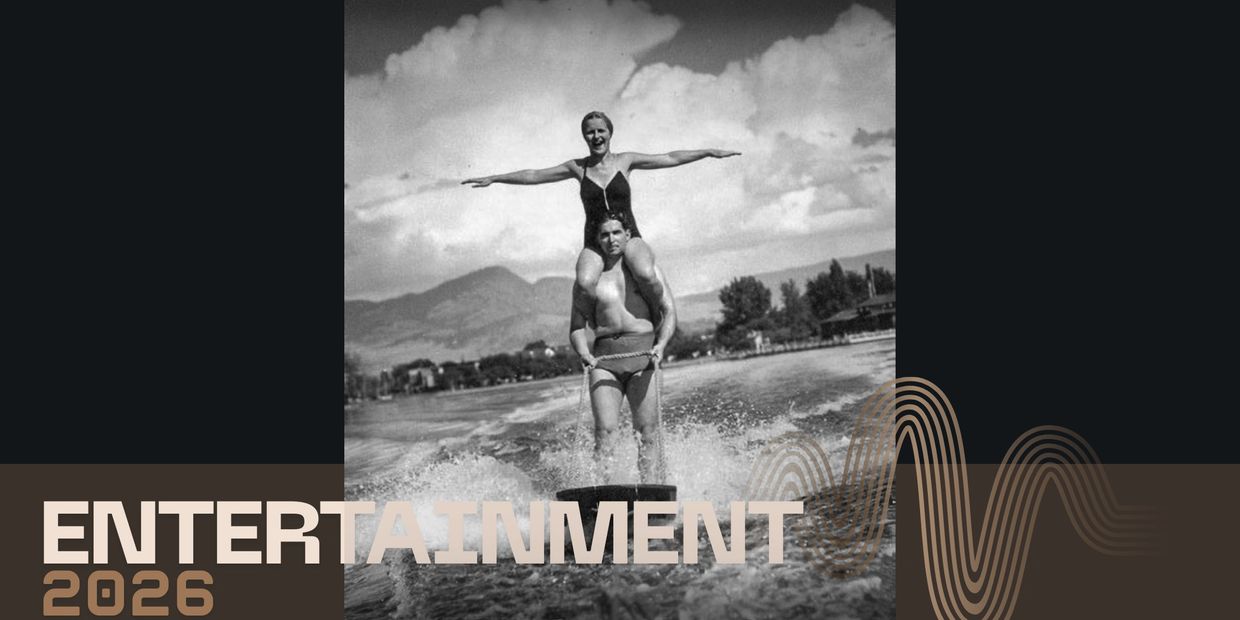 Black and white photo of a man waterskiing with a woman on his shoulders.