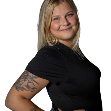 Smiling woman with blonde hair and floral tattoos on her arm.