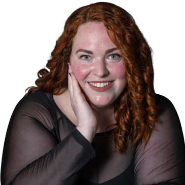 Smiling woman with curly red hair wearing a sheer black top.