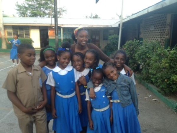 Adults in a classroom setting reviewing papers, with a female teacher standing.
