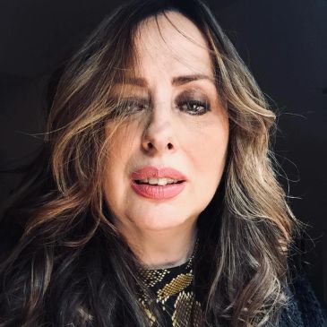 Close-up portrait of a woman with wavy hair and natural makeup.