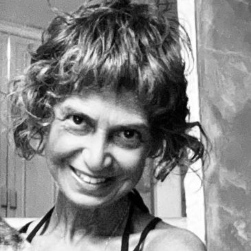 Smiling woman with curly hair in a black and white portrait.