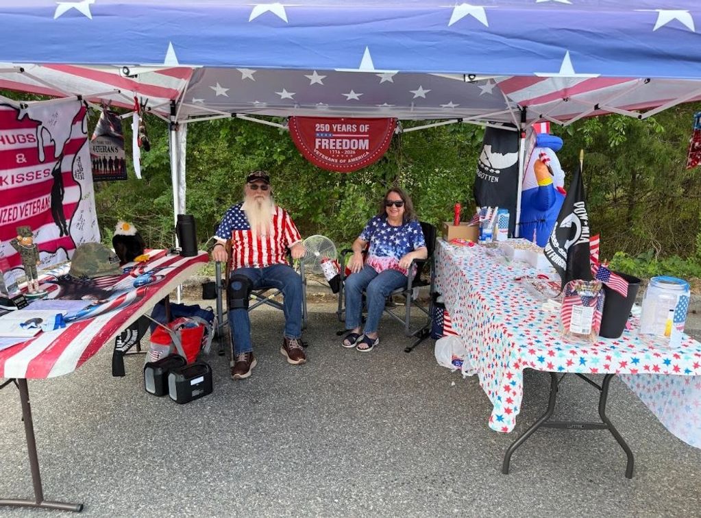 Two people at a patriotic booth celebrating 250 years of American freedom.